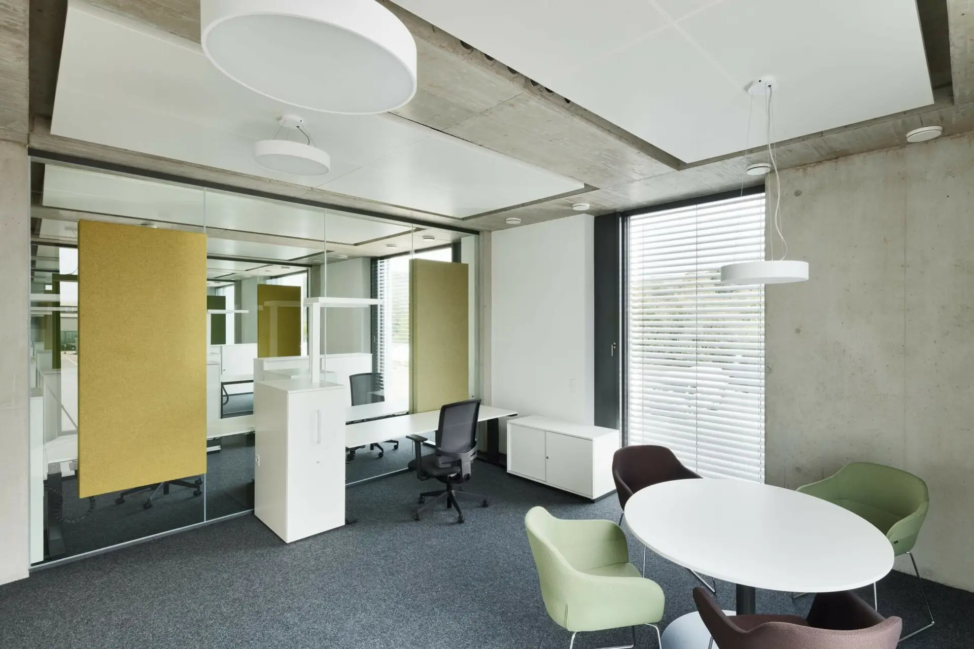 Modernes Büro mit Glaswänden, gelben Paneelen, weißem Schreibtisch, Besprechungstisch und farbigen Stühlen.